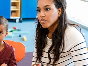 School-based professional talking with a parent and child in a brightly lit classroom, discussing school violence support strategies.