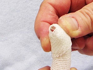 A hand bandaging a finger on light blue fabric, with Medbridge branding.