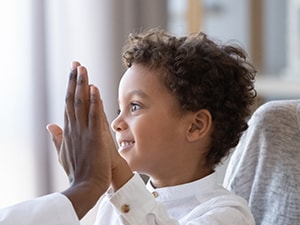 A child high-fives a Medbridge clinician with a smiling woman beside them.