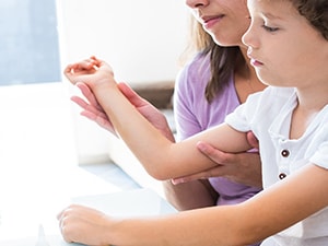 A child on a woman's lap participates in an online doctor consultation via Medbridge.