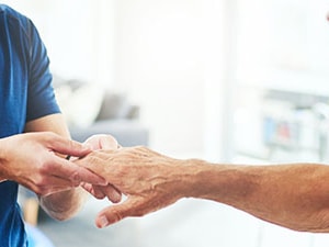 Therapist examining a patient's finger and hand during treatment for Boutonnière deformity in a clinical setting.