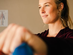 Woman performing a resistance band shoulder exercise as part of a rotator cuff rehabilitation program.