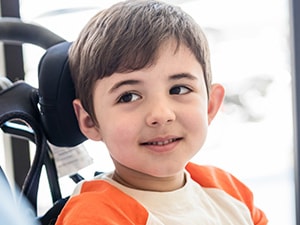 Child in wheelchair looking at clinician, illustrating the importance of head positioning in wheelchair seating support.