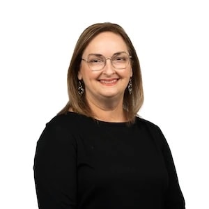 Woman with shoulder-length brown hair, glasses, and a black top smiles at the camera, representing a medbridge digital health pro.
