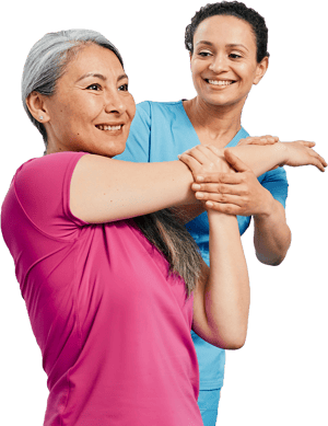 A smiling woman in a pink shirt stretches her arm with assistance from another smiling woman in a blue shirt, symbolizing medbridge's digital healthcare support.