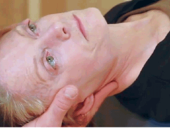 A person lying down receives a chiropractic neck adjustment with emphasis on the practitioner's hand positioning.