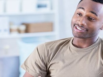 A Medbridge employee in a brown shirt talks to someone in a white coat in an office.
