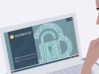 Individual viewing a laptop with a medbridge-branded information security presentation showing a digital lock graphic.