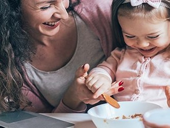 Woman and child dining happily at a table with a nearby laptop showing medbridge.