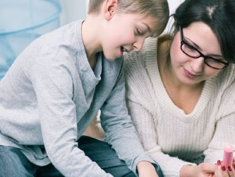 A woman and a boy make crafts with colorful paper and glue.