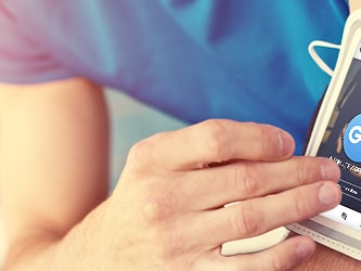 A person in athletic wear uses a smartphone in a white armband holder with the medbridge music app displaying a blue GO button.