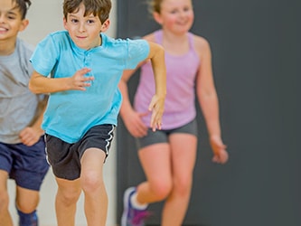 Children running energetically inside a gym.