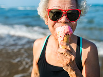 Older adult enjoying cold ice cream by the beach, representing the sensory role of cold in a dysphagia diet.