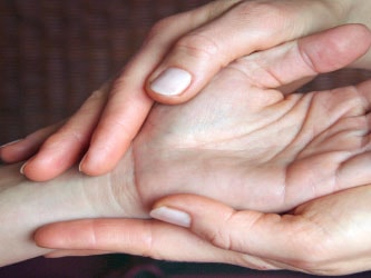 Hands gently holding another's palm, Medbridge style.