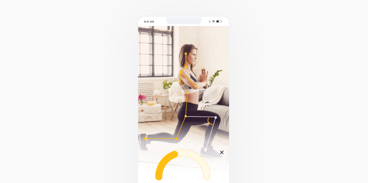 A woman lunges in her living room while a fitness app on her phone tracks her form.