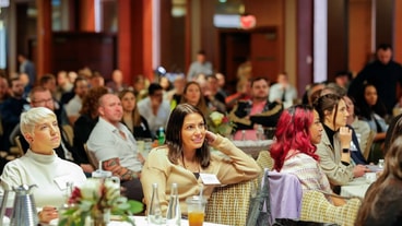 People at round tables in a conference setting listen to an off-camera speaker, relating to medbridge.