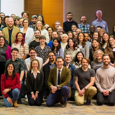 A diverse group of people posing indoors, wearing casual and business attire for medbridge.