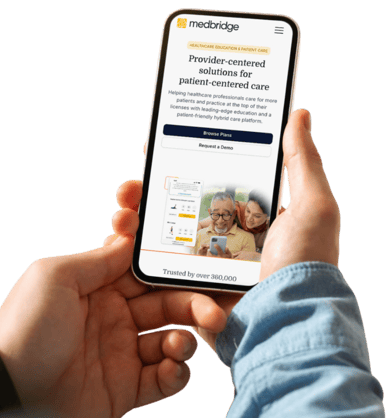 A person holds a smartphone showing the medbridge website.