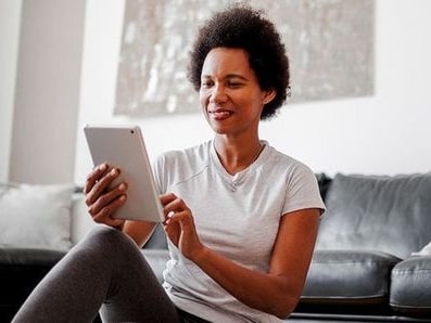 A person uses a tablet near a blue exercise ball in a living room.