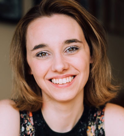 A smiling person with shoulder-length brown hair in a floral top represents medbridge's integration of warmth and technology in healthcare.