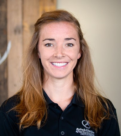 Woman with long brown hair in a black collared shirt smiles at the camera, representing medbridge healthcare software.
