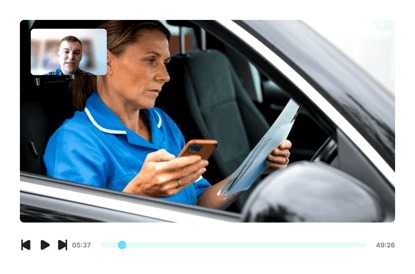 A woman in a blue uniform sits in a car with a phone and document, participating in a Medbridge video call.