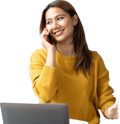 A person in a yellow sweater smiles while discussing digital healthcare on the phone at their desk with a medbridge laptop.