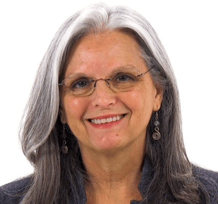 A smiling woman with long gray hair, glasses, and earrings represents hybrid care on a white background.