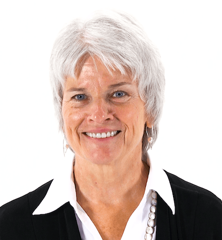 An older individual with short white hair, wearing a black jacket and pearl necklace, represents compassionate care in healthcare education for medbridge.