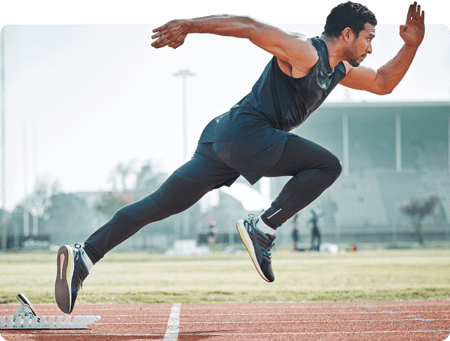 A man sprints from starting blocks on an outdoor track in daylight, symbolizing medbridge motivation.