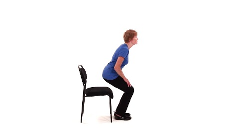 A person performs a chair squat exercise as part of medbridge digital healthcare training.