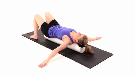 A person on a black exercise mat uses a foam roller, highlighting medbridge's integration of physical well-being and digital healthcare.