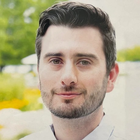 A man with short dark hair and a beard stands outdoors with greenery, representing medbridge's vision for digital healthcare.