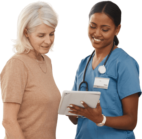 A healthcare professional in blue scrubs shows a tablet to an older woman.