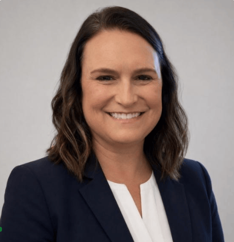 Woman with shoulder-length brown hair in a navy blazer and white blouse smiles at the camera, representing medbridge digital healthcare.