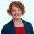 A smiling person with short curly hair in a teal blazer and red top symbolizes Medbridge's digital healthcare innovation.