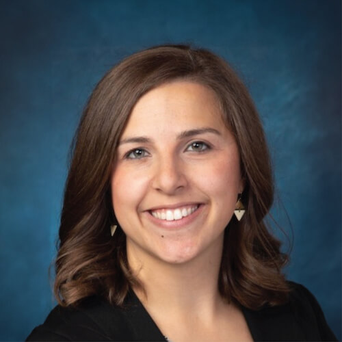 A person with brown hair and triangle earrings smiles against a blue background in Medbridge.