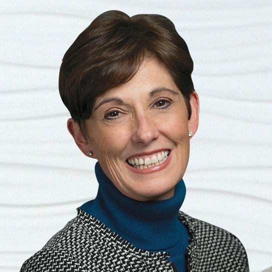 A smiling person embodies innovation in digital healthcare, styled in a blue turtleneck and patterned jacket; medbridge.