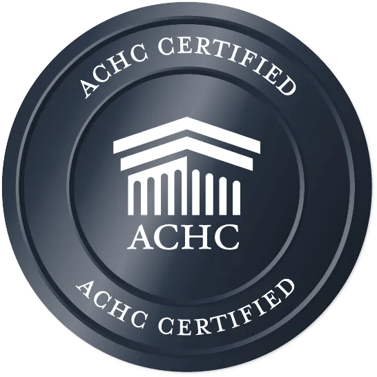 ACHC Certified emblem with a stylized architectural icon and "ACHC Certified" text on a dark circular background, related to medbridge.