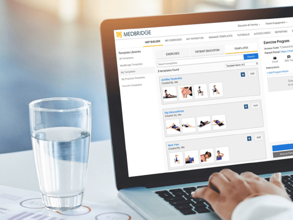 Individual using a laptop with the medbridge exercise program interface, alongside water and documents.