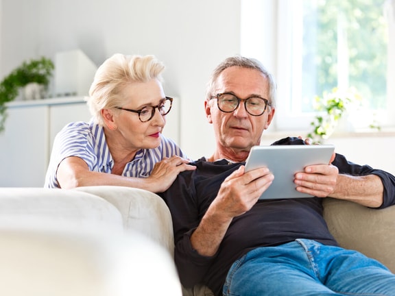 Older couple using a tablet together at home, illustrating engagement with technology among the "silver tsunami" generation.