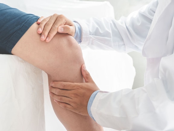 Orthopedic clinician examines a patient's knee during a joint replacement recovery assessment