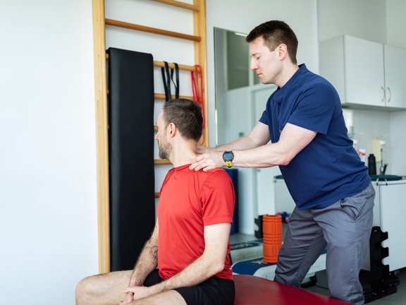 Physical therapist evaluating cervical mobility in a patient during concussion management in a clinical rehab setting.