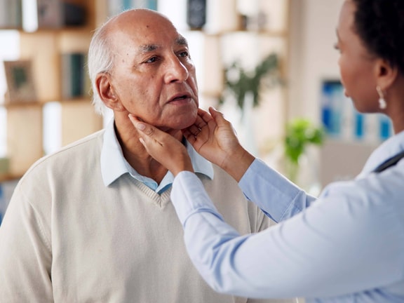 Clinician palpates patient’s neck during swallow exam, assessing for signs of esophageal dysphagia.