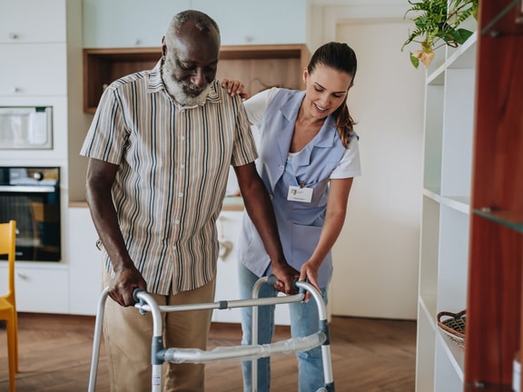female clinician helping senior male walking - functional independence measure