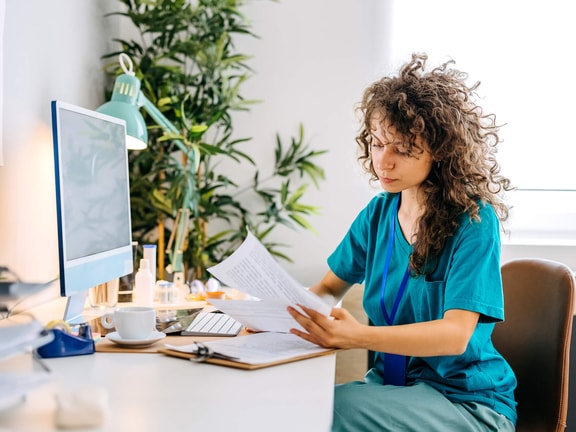 Healthcare professional reviewing billing documents at desk, illustrating use of GP modifier, KX modifier, and GA modifier.