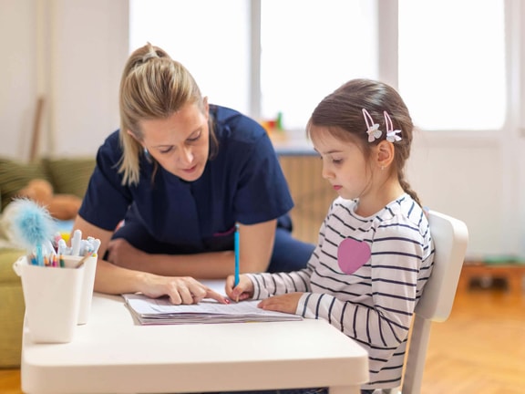 Occupational therapist helping a child with handwriting to support motor skills and executive functioning.