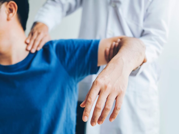 Physical therapist assisting a patient’s shoulder as part of a referral assessment.