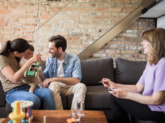 Pediatric occupational therapist coaching parents and child at home during a family-centered therapy session