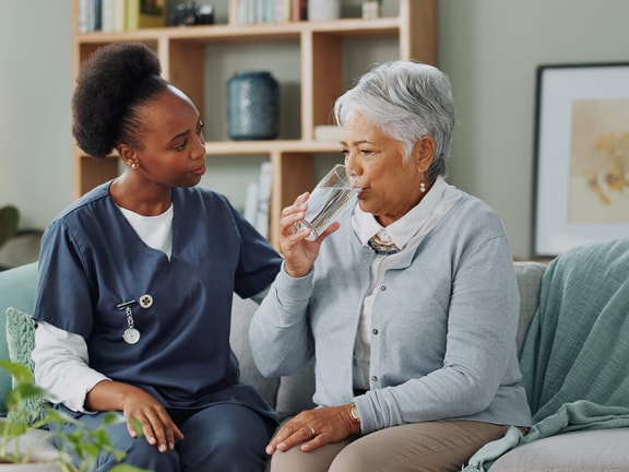 Speech-language pathologist assisting patient with safe swallowing techniques during dysphagia management therapy.